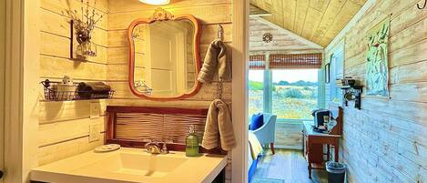A rustic bathroom with a wooden interior, a large mirror, a sink, and a towel hanging on the wall.
