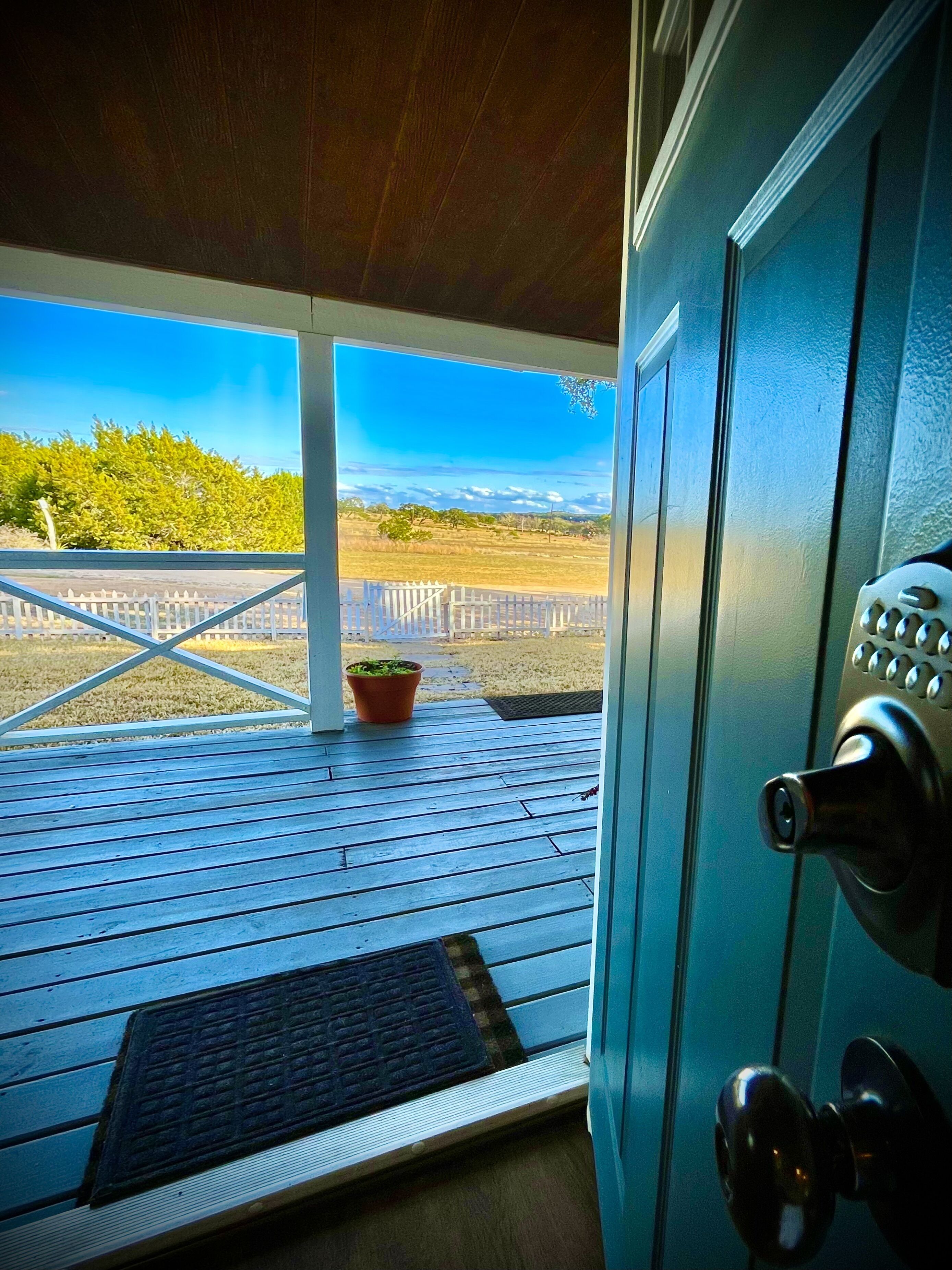 Une terrasse en bois offrant une vue sur un champ clôturé et sur des collines lointaines.