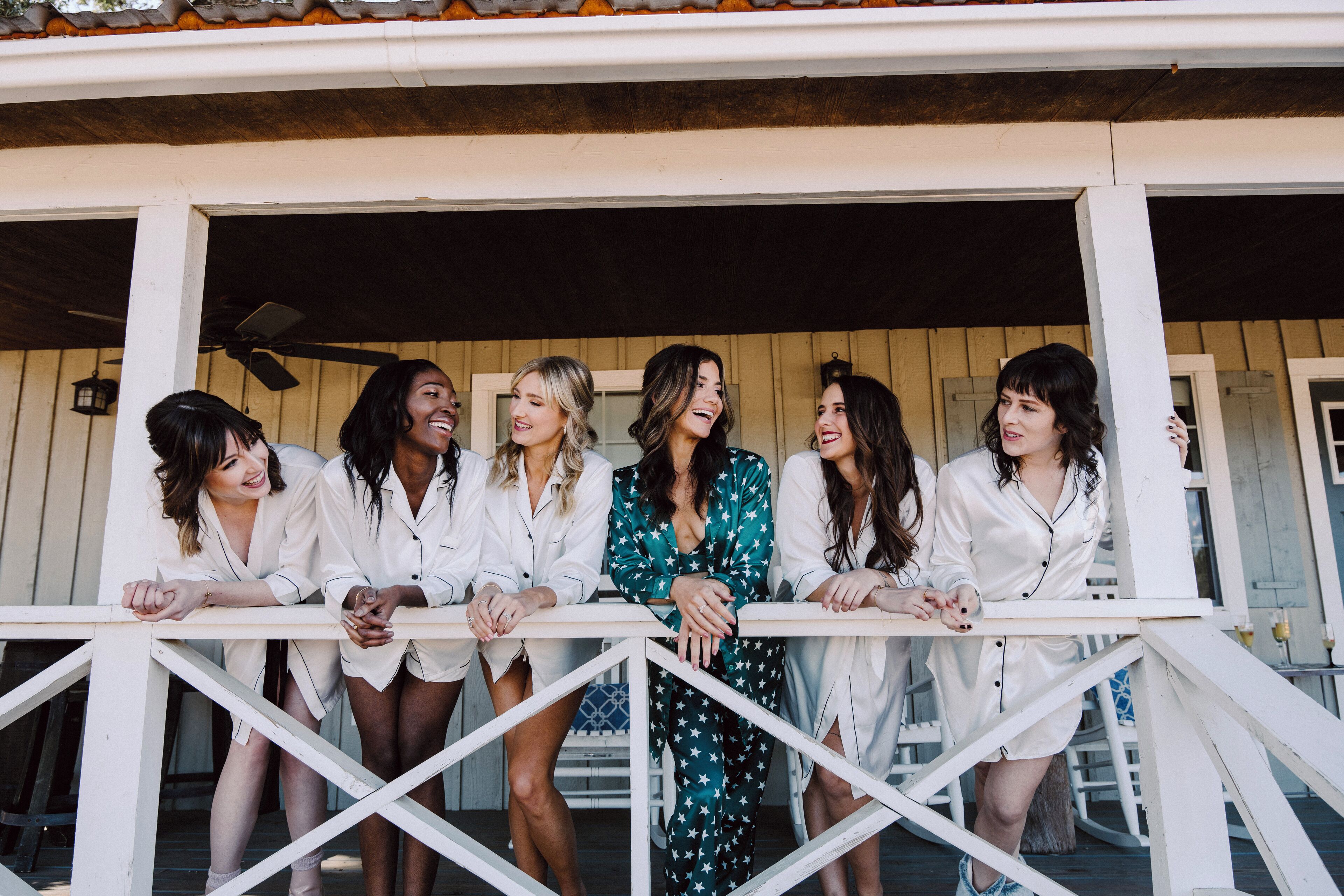 A group of people standing on a porch with a wooden railing.