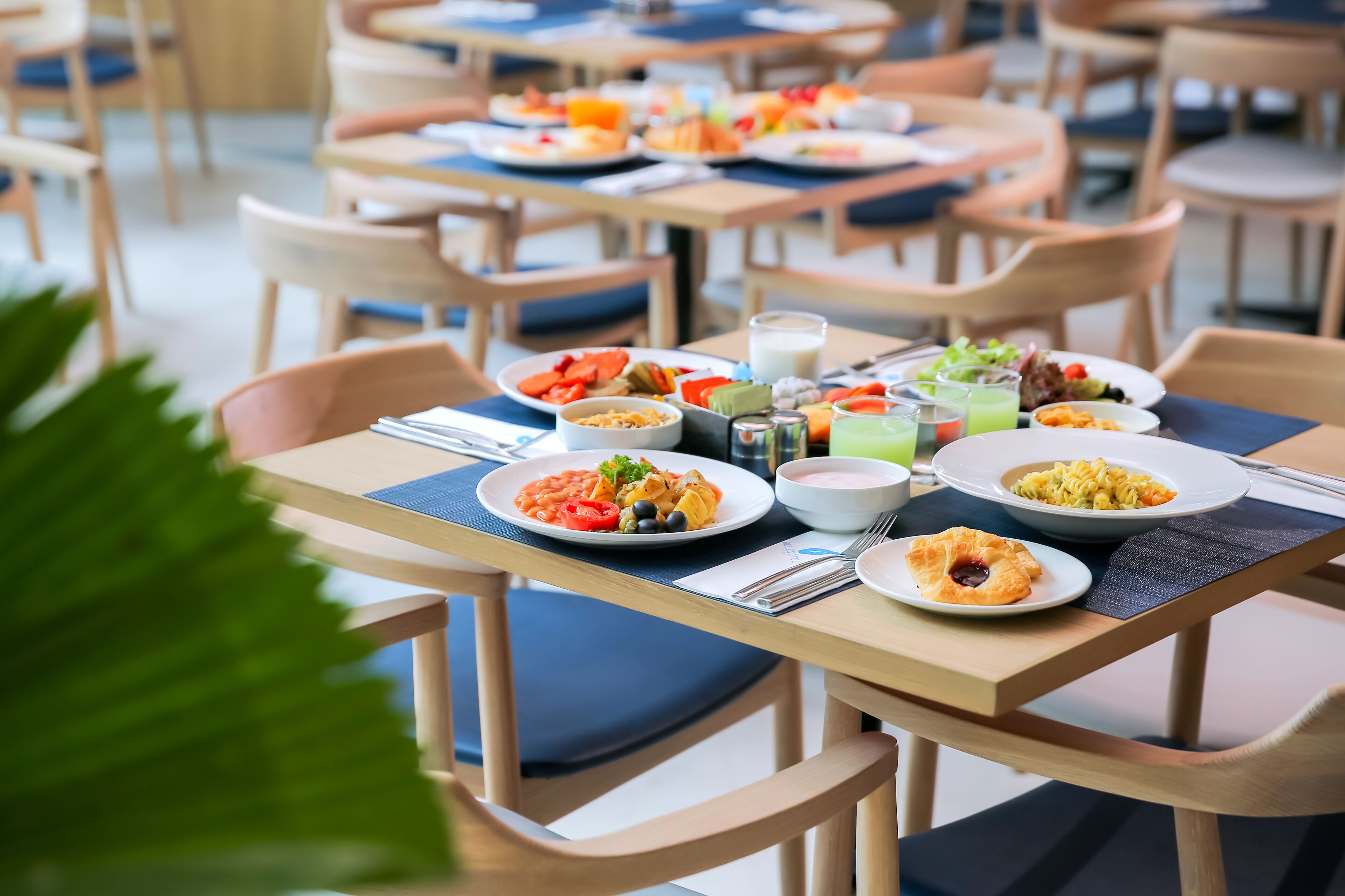 A dining area with multiple tables, each set with plates of food, drinks, and cutlery.