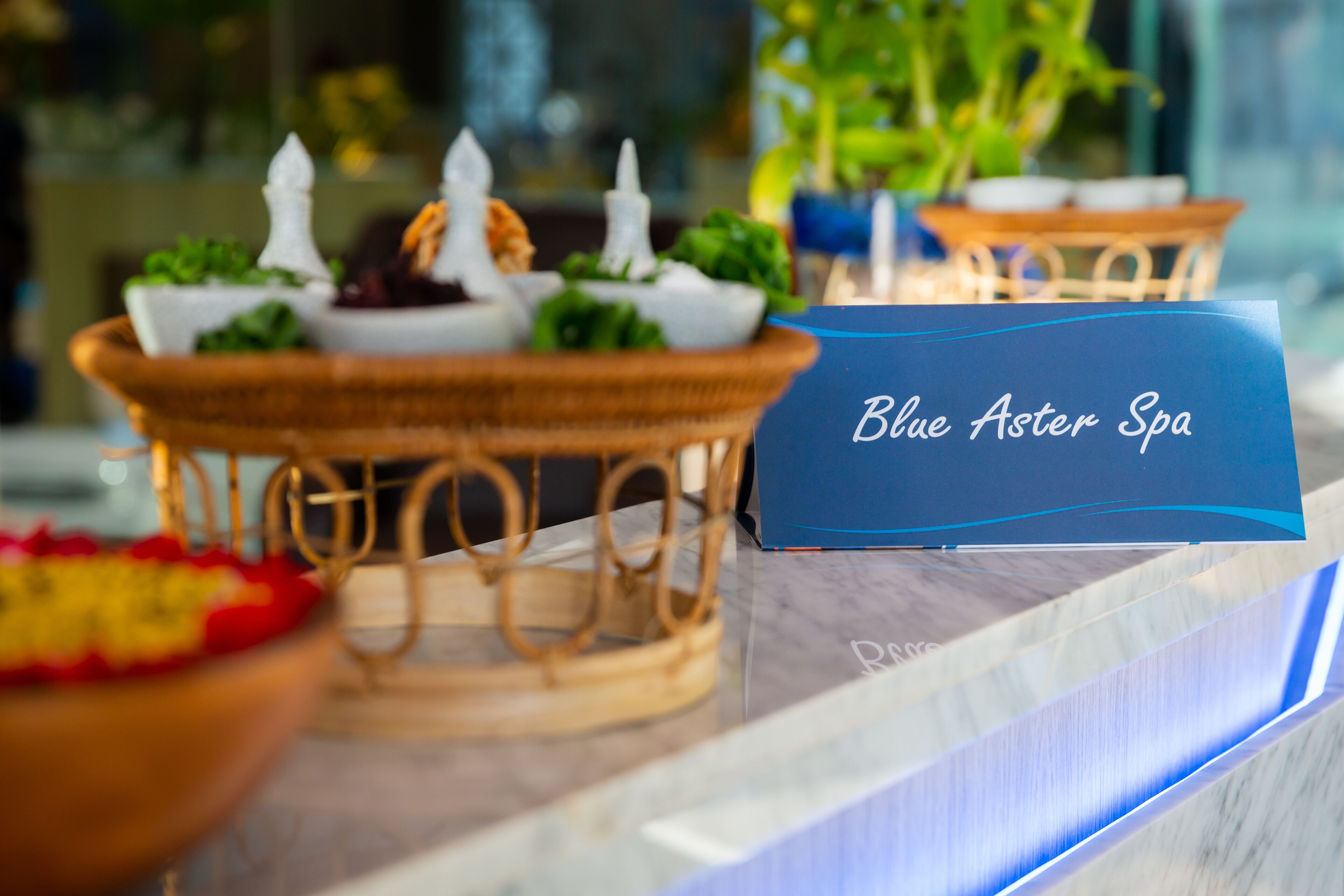 Een receptie met een bord waarop 'Blue Aster Spa' staat en een decoratieve presentatie van eten en kaarsen.
