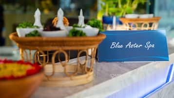 Een receptie met een bord waarop 'Blue Aster Spa' staat en een decoratieve presentatie van eten en kaarsen.