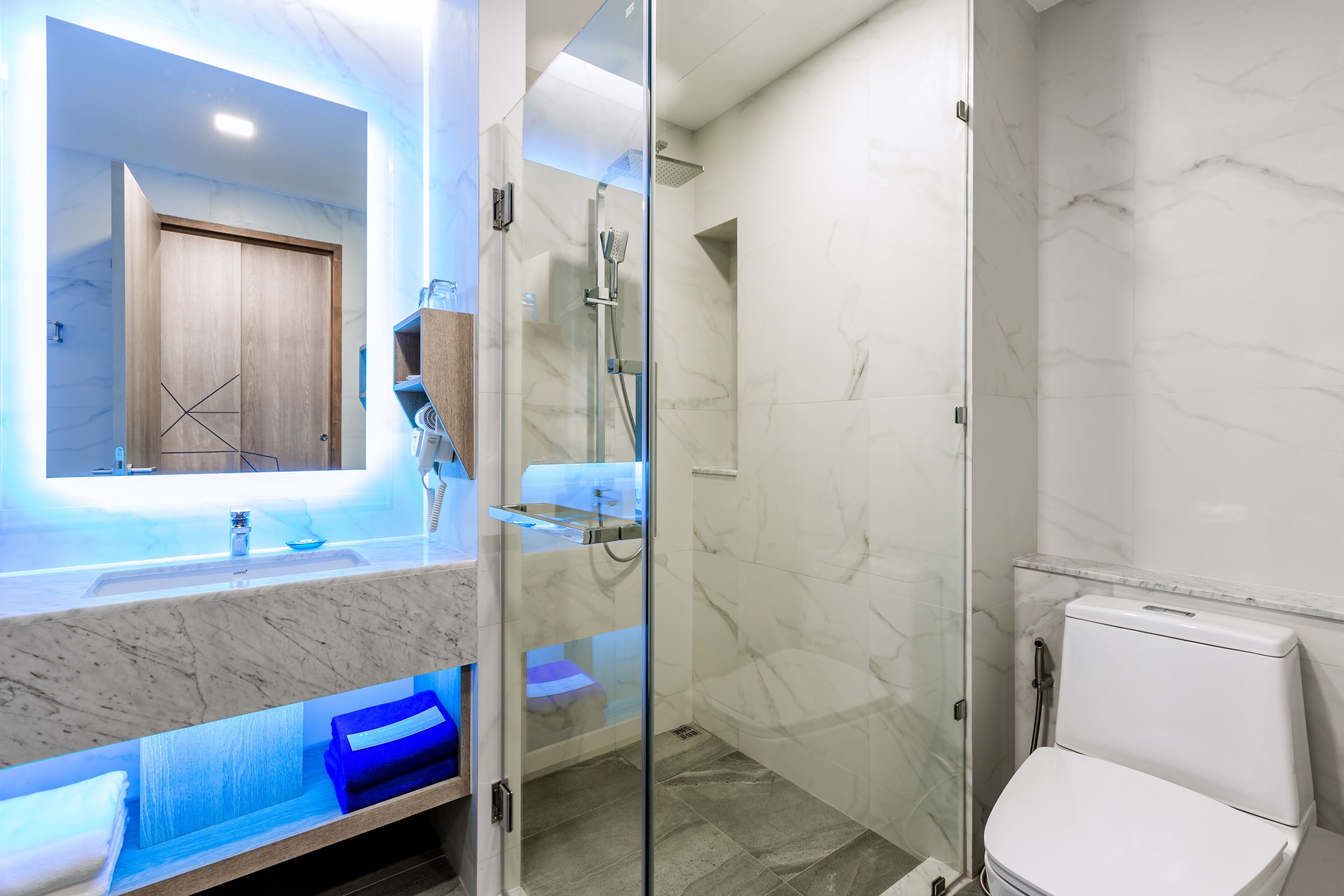 A modern bathroom with a glass-enclosed shower, a marble sink, and a toilet.