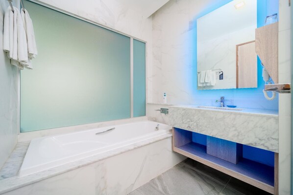 A modern bathroom with a bathtub, a large mirror, and a vanity with a sink.