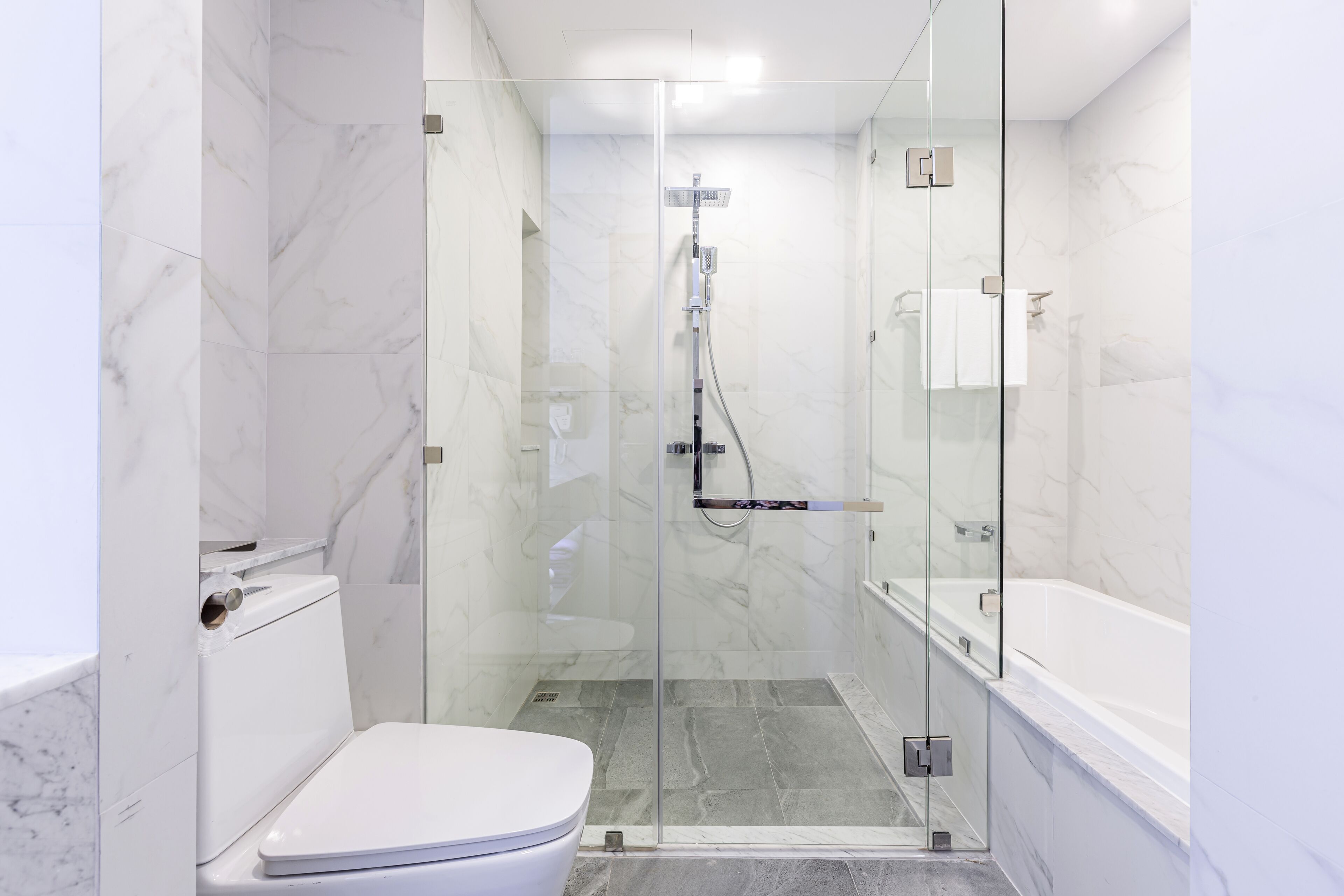 A modern bathroom with a glass-enclosed shower, a white toilet, and a bathtub.