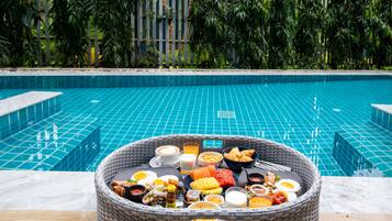 Una cesta de mimbre con artículos de desayuno sobre una mesa junto a la piscina.