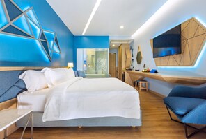 Una habitación de hotel moderna con una cama grande, un escritorio y un televisor montado en la pared.