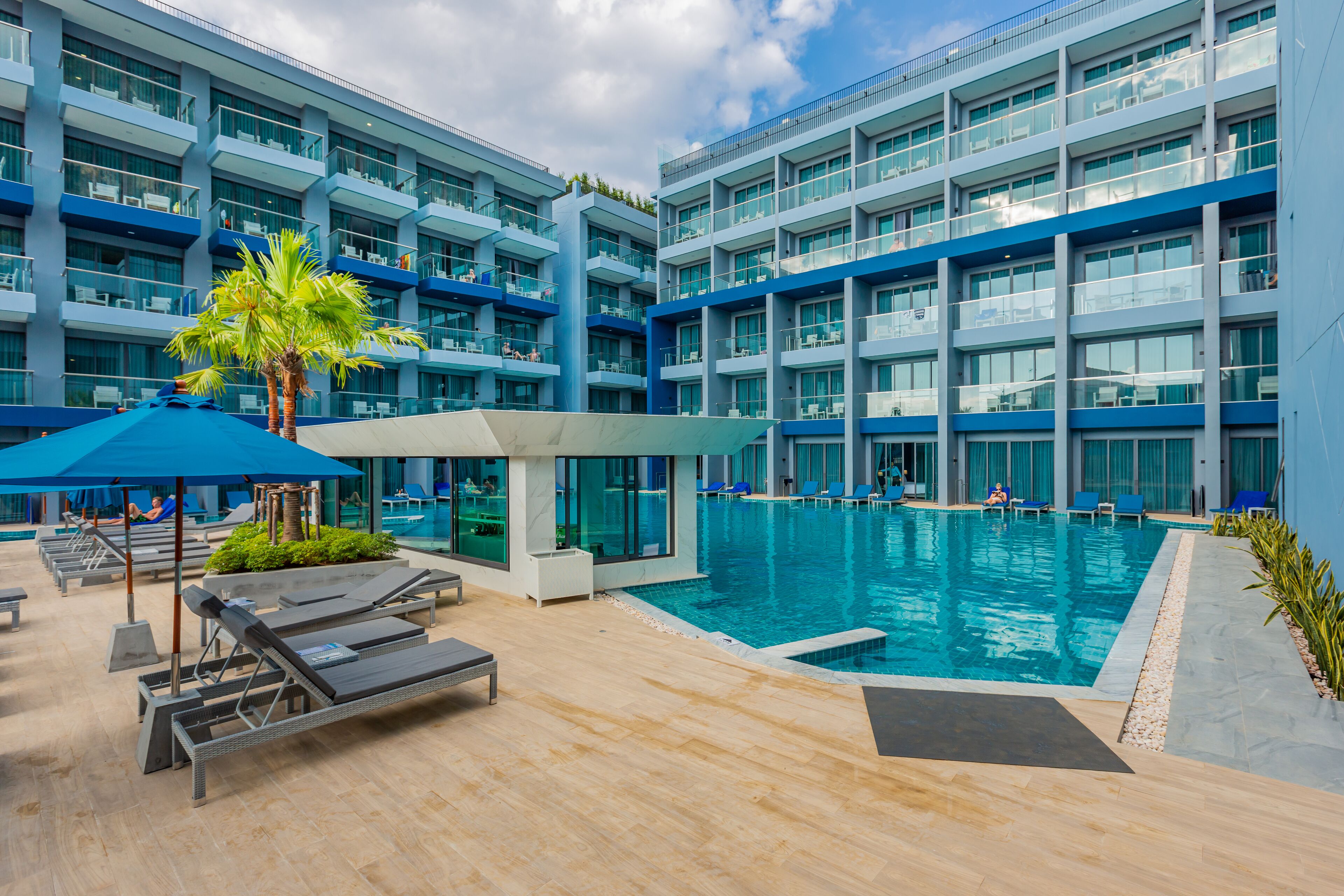 A modern hotel with a large indoor swimming pool, multiple balconies, and sun loungers.