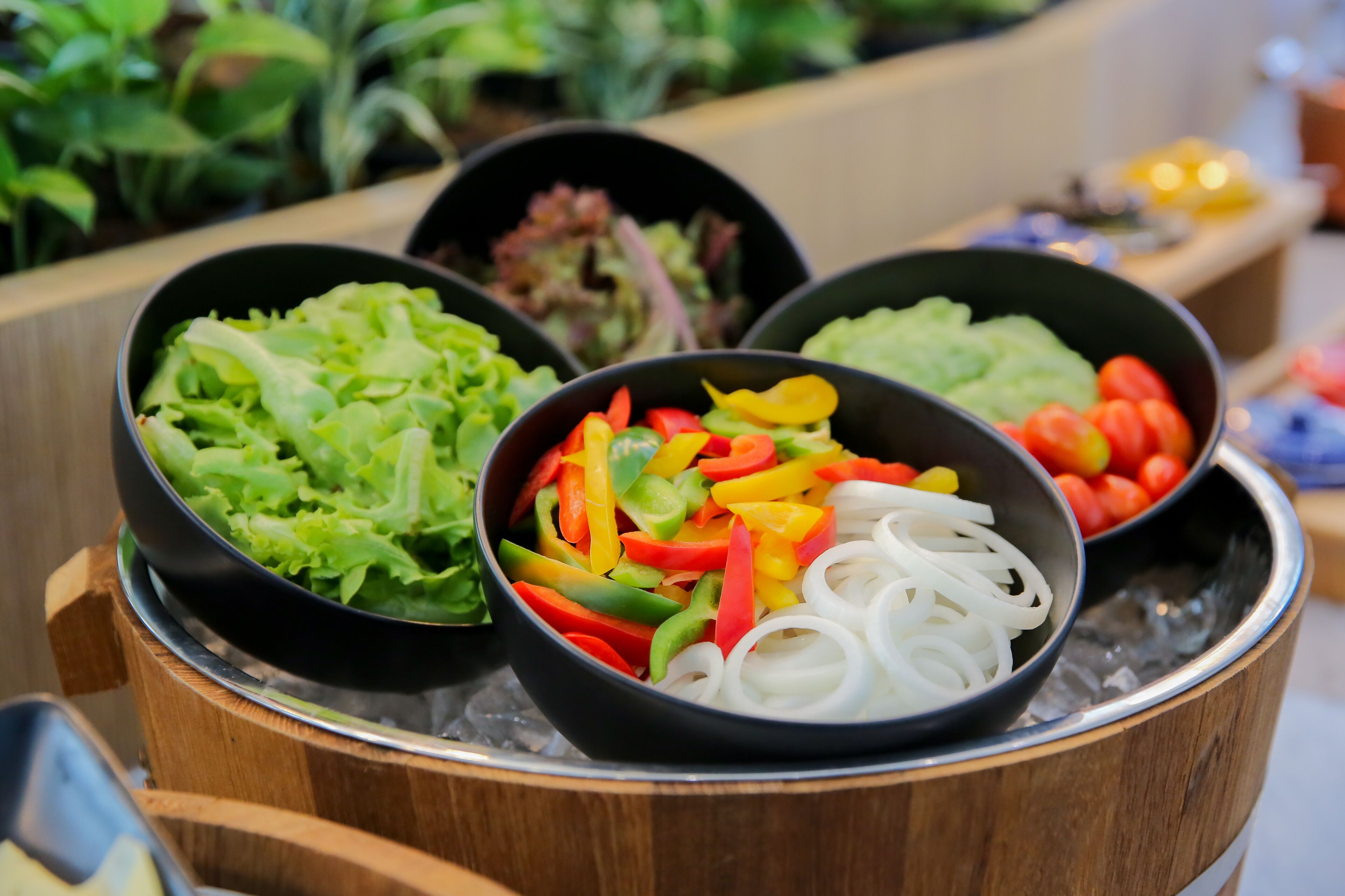 Trois bols de légumes frais, présentés sur un présentoir en bois.
