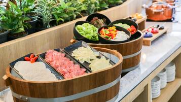 Un bufé con diversos alimentos, incluyendo carnes, verduras y salsas en recipientes de madera.