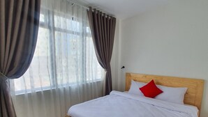 A bedroom with a wooden bed, white bedding, and a red pillow. - Hello Dalat Hostel (Xuan Huong - Da Lat)
