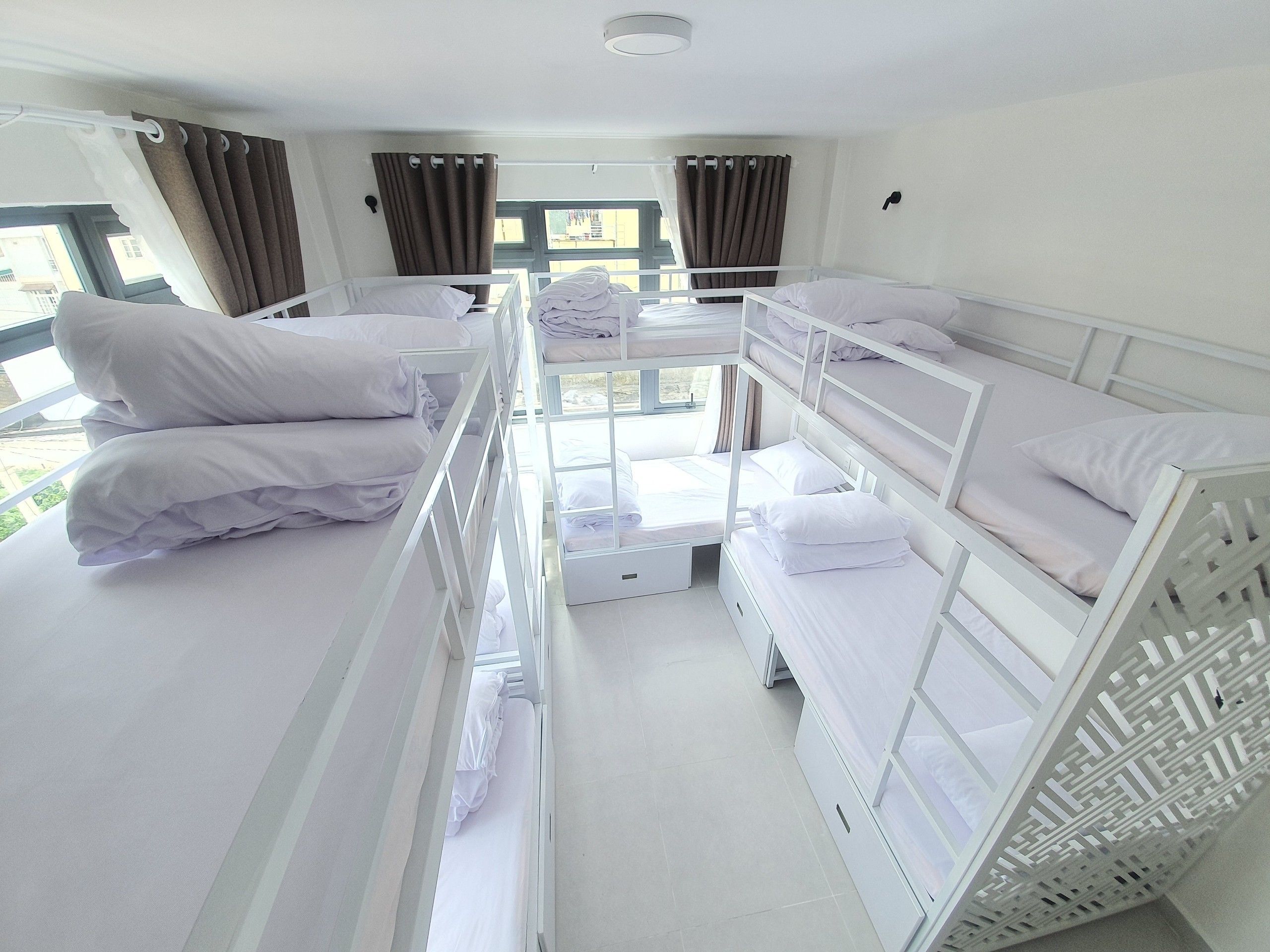 A hotel room with bunk beds, a window with curtains, and a view of the outside.