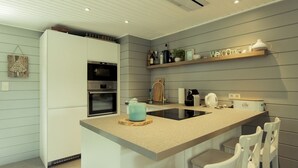Una cocina moderna con una isla central, horno integrado y un cartel de bienvenida en la pared.