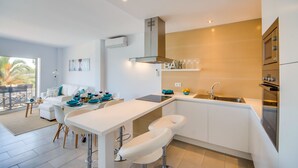 A modern kitchen with white cabinetry, a central island, and a built-in oven. - Apartment in Alcudia Enjoy near the beach (Alcúdia)