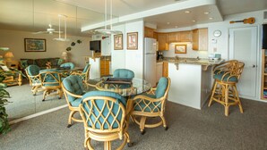 Une cuisine moderne dotée d’un îlot central, de meubles en bois et d’un coin repas avec des chaises en osier et une table en verre.