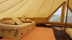 Une tente équipée d’un lit, d’oreillers et d’un tapis à motifs.