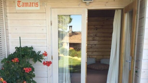 Una cabana de fusta amb un rètol que diu "Tamaris" sobre la porta.