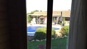 Habitació amb vista a una piscina, un patí i un edifici amb teulada de rajola.