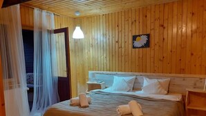 A wooden-paneled room with a bed, a nightstand, a lamp, and a painting of a daisy.