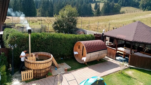 A rustic outdoor setting with wooden barrels, a hot tub, and a tent.