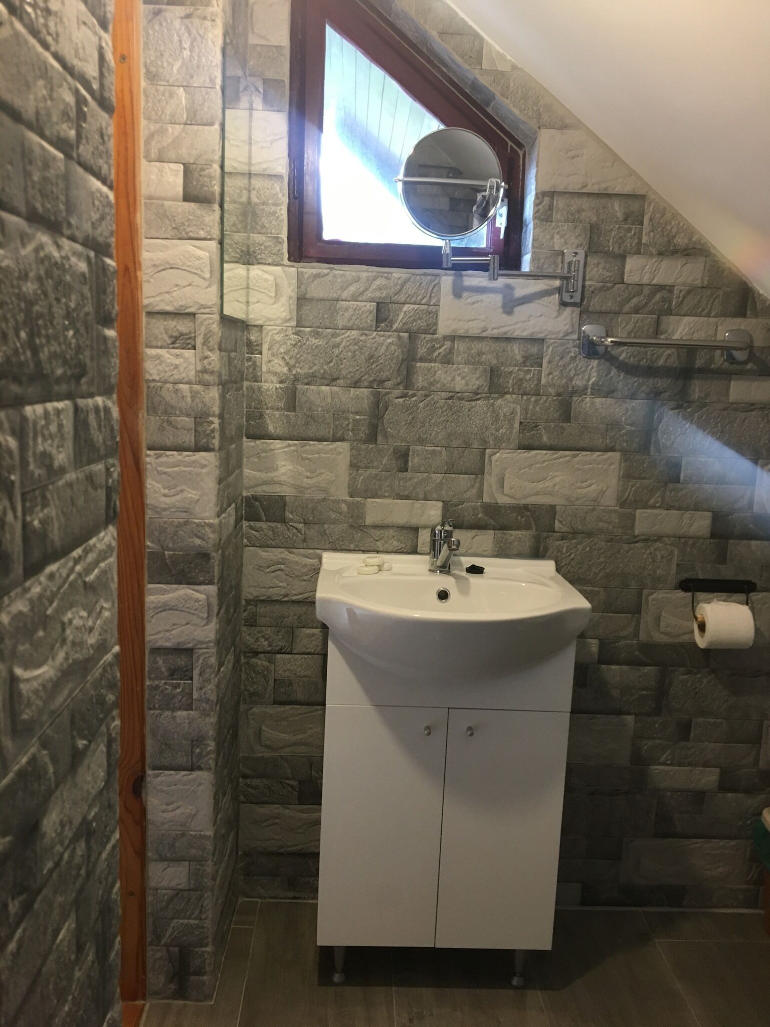 A bathroom with a stone wall, a white sink, and a wooden door.