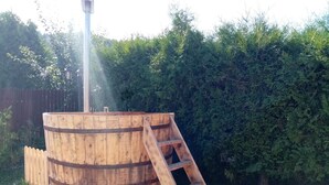 A wooden barrel structure with a ladder, surrounded by greenery and a wooden deck.