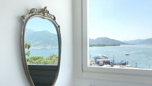 A room with a large mirror reflecting a view of a lake, boats, and distant mountains. - Iseo Lake View - the window on the harbor (Iseo)