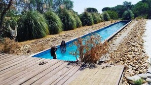 Una piscina con cubierta de madera y vegetación circundante.