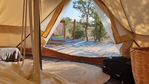 Una carpa con una cama, una mesita y una cesta de mimbre.