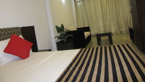 Una habitación de hotel con cama, sofá, una mesita y una planta en maceta.