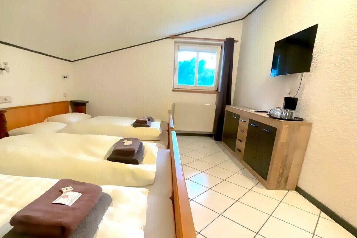 Une chambre d’hôtel avec deux lits, une télévision, une fenêtre et une petite kitchenette.