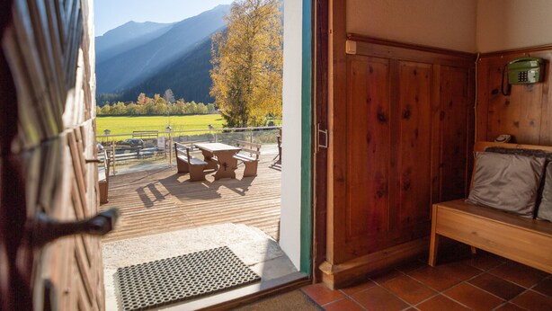 Un intérieur en bois offrant une vue sur un paysage montagneux, visible à travers une porte ouverte.
