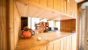 Un intérieur en bois avec un comptoir d’accueil, une petite décoration sur le thème de la citrouille et une pomme de pin.
