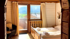 Une chambre confortable avec un plafond en bois, un lit, une petite table et une chaise.