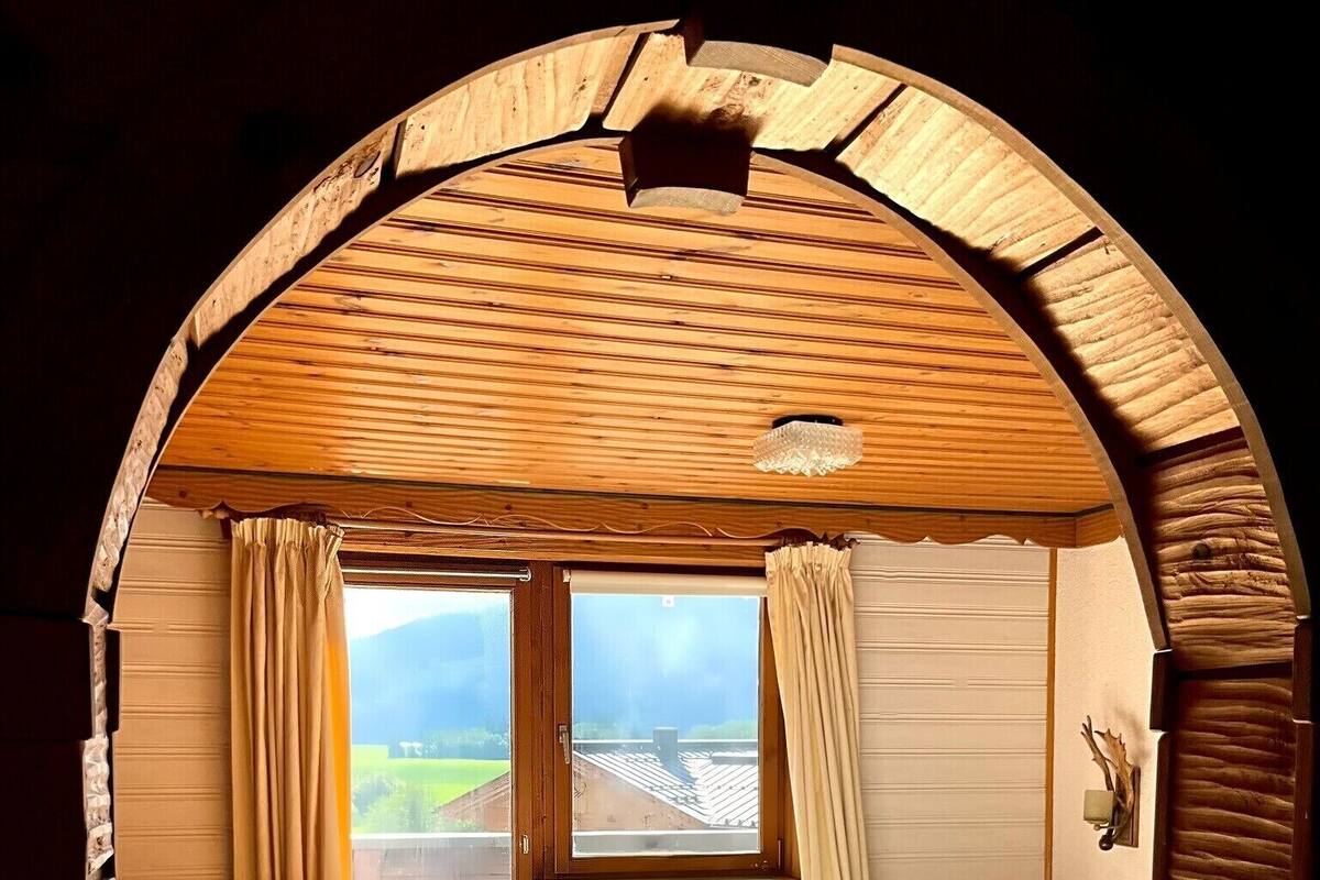 Une chambre confortable avec un plafond en bois, un lit, une petite table et une chaise.