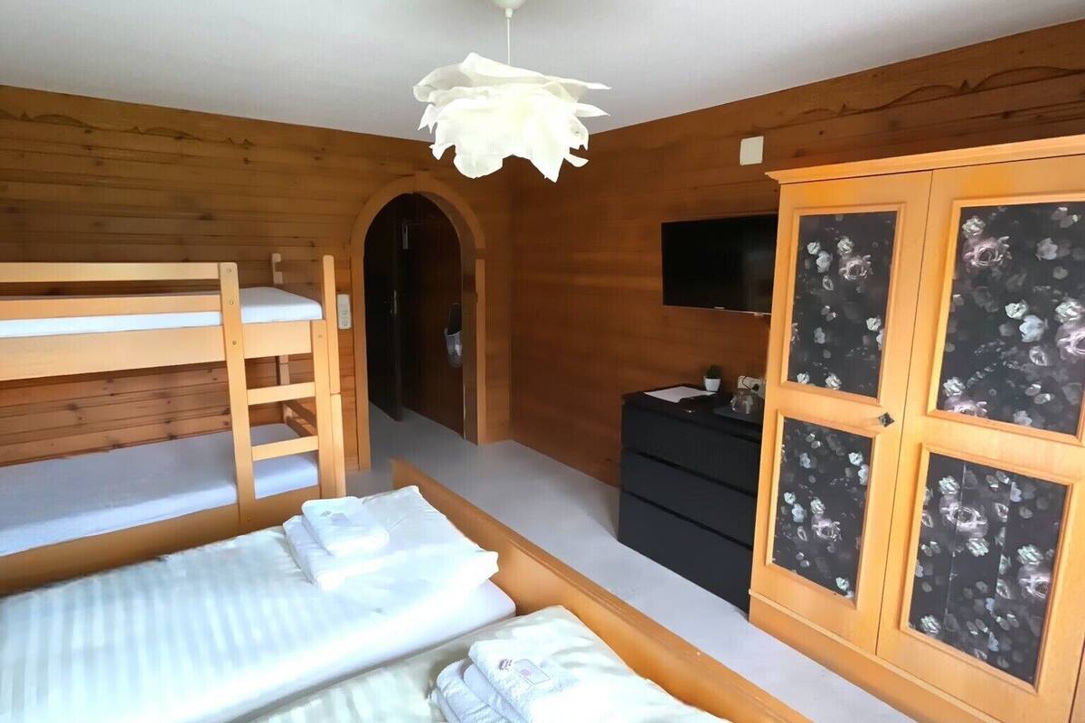 Une pièce avec deux lits superposés, une armoire en bois ornée de motifs floraux et un luminaire fixé au plafond.