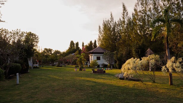 A house surrounded by a well-maintained garden with various plants and trees. - Long-Maa-Doo-Resort (Suan Phueng)