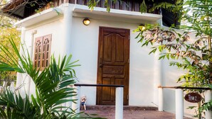 A white building with a wooden door and steps leading up to it. - Long-Maa-Doo-Resort (Suan Phueng)