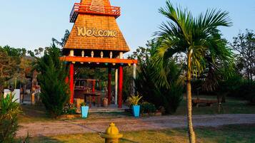 A windmill with a 'Welcome' sign, surrounded by greenery and a yellow fire hydrant.