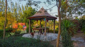 A gazebo with a tiled roof, surrounded by lush greenery and a stone pathway. - Long-Maa-Doo-Resort (Suan Phueng)