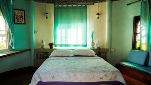 A bedroom with a bed, a nightstand, a lamp, a window with curtains, and a view of the outside. - Long-Maa-Doo-Resort (Suan Phueng)