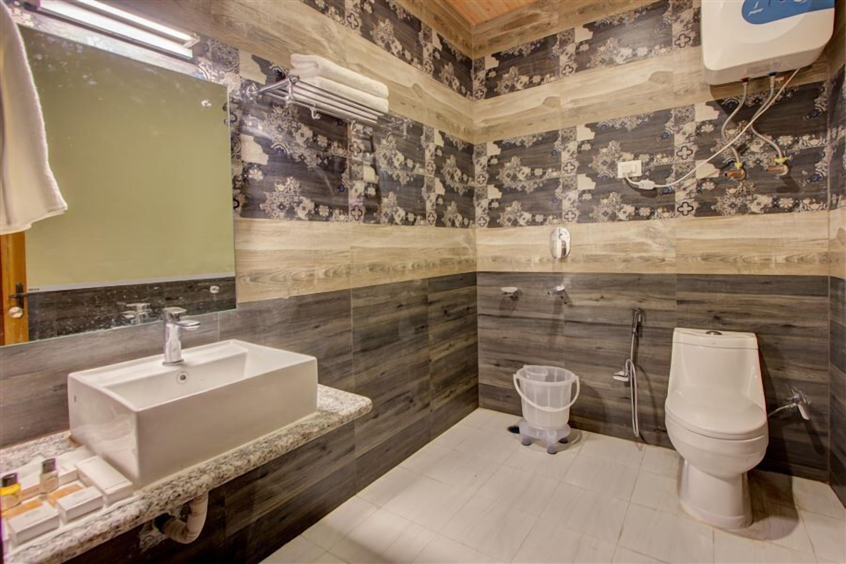 Baño con lavabo, inodoro y ducha. Las paredes presentan un diseño de azulejos estampados.