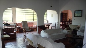 A spacious living area with a large sofa, a chair, and a small table. There are arched windows providing natural light.