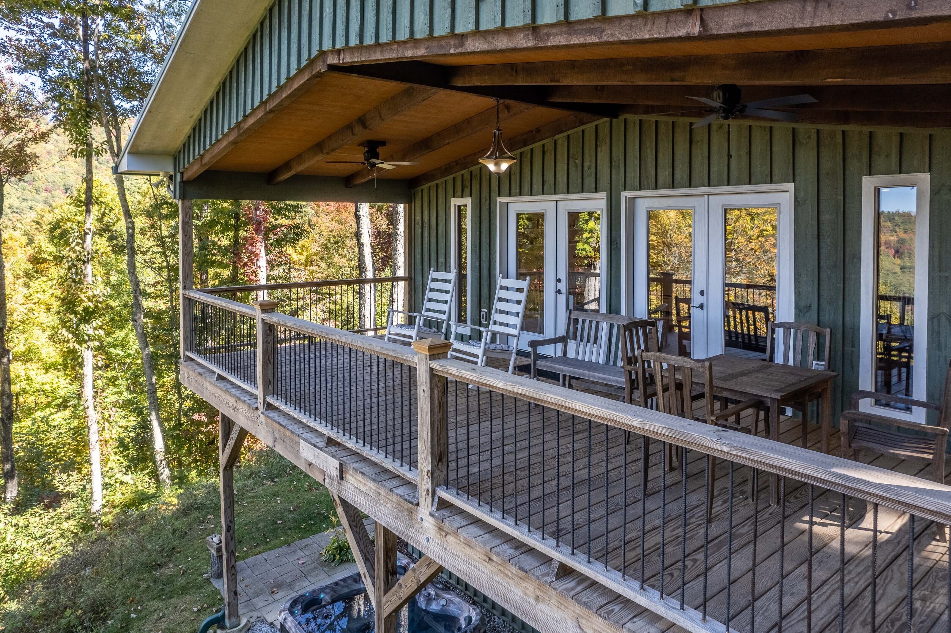 Une terrasse en bois avec des meubles d’extérieur, un foyer et une vue sur la forêt environnante.