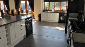 A modern kitchen with a built-in washer and dryer, a large island with a sink, and a view of the backyard through large windows. - Quiet setting with secure gated parking, children's play area & farm animals (upwell)