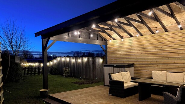 An outdoor patio with a wooden deck, a covered seating area, and a view of the surrounding landscape. - Quiet setting with secure gated parking, children's play area & farm animals (upwell)