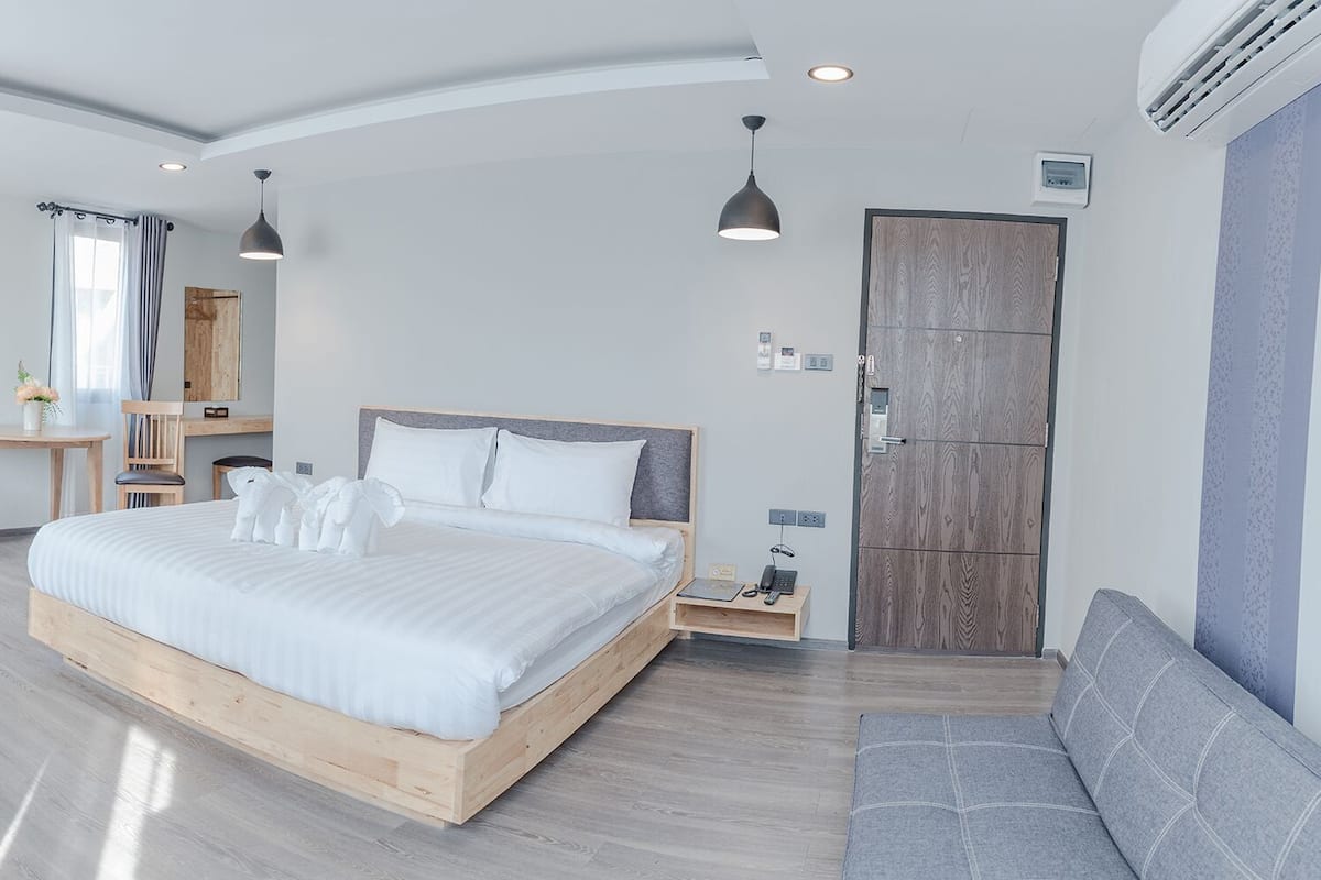 Quarto moderno com cama grande, mesas de cabeceira, escrivaninha e uma cadeira.