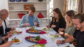Un grupo de personas cenando en una mesa con diversos platos y copas de vino.