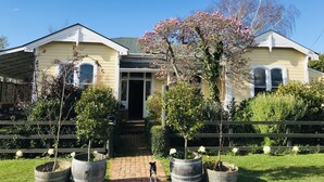 Una casa de dos pisos con un porche delantero, un buzón y un perro de pie en la entrada.