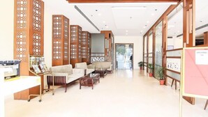 A spacious lobby with a reception desk, seating area, and decorative wooden panels. - Hotel Vikram Palace (Varanasi)